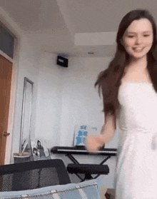 a woman in a white dress is dancing in a living room next to a keyboard .