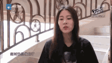 a woman in a black t-shirt is sitting in front of a wrought iron railing with the word voice written on it
