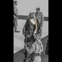 a man in a military uniform holds a gun while standing next to another man