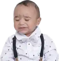 a baby is wearing suspenders and a bow tie and crying