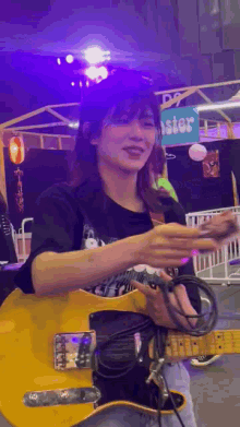 a woman is playing a yellow electric guitar in a room .