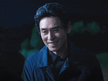 a man wearing a black shirt and a blue jacket is smiling