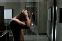 a shirtless man washing his head in a bathroom