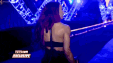 a woman in a black dress is walking on a stage in front of a crowd .