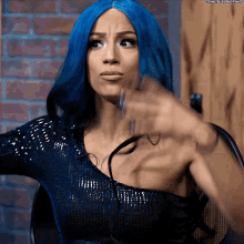a woman with blue hair is sitting in a chair and making a face