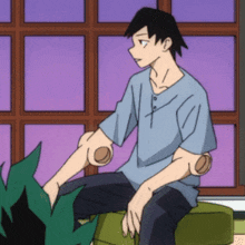 a man in a blue shirt is sitting on a couch with his arms crossed