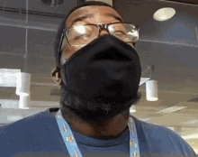 a man wearing glasses and a black mask looks up