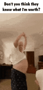a man with a very large belly is dancing in a living room with his arms in the air .