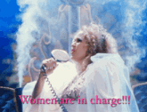 a woman in a white dress is holding a hair dryer and the words women are in charge are behind her
