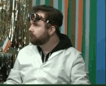 a man with a beard wearing goggles and a lab coat