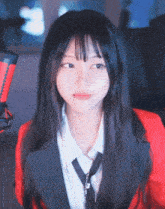 a girl wearing a red jacket and tie is looking at the camera