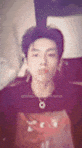 a blurry picture of a young man wearing a t-shirt and a necklace .