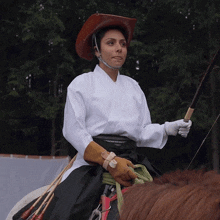 a woman wearing a cowboy hat and gloves is riding a horse