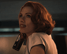 a woman with red hair holds a bottle over her shoulder that says ' coca cola ' on it
