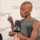 a woman is talking into a microphone in front of a wall that says national board view