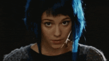 a close up of a woman with blue hair looking at the camera