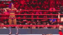 two women are wrestling in a wrestling ring while a crowd watches .