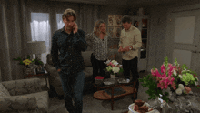 a man in a plaid shirt talks on a cell phone in a living room