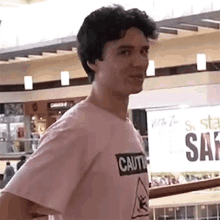 a young man wearing a pink shirt that says caution