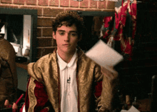 a young man wearing a crown is holding a piece of paper in his hand