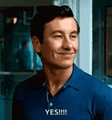 a man wearing a blue shirt is smiling and saying yes .