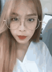 a young woman wearing glasses and a white shirt looks at the camera
