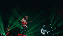 a man playing a guitar on a stage with a shirt that says ban on it