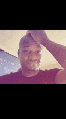 a man in a black shirt is smiling and holding his hand to his head