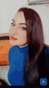 a woman wearing a blue turtleneck and red lipstick has a blue plus sign next to her