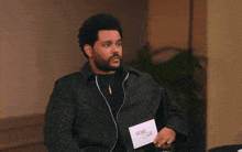 a man in a green jacket is holding a piece of paper that says gq