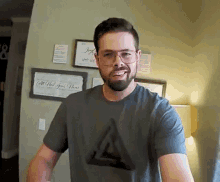 a man with a beard wearing glasses and a t-shirt with a triangle on it