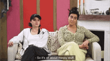two women are sitting on a couch and one of them is saying so it 's all about messy stuff