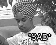 a black and white photo of a man wearing a turban and a sad shirt