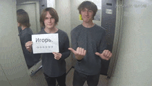 two young men in an elevator holding a sign that says igorb