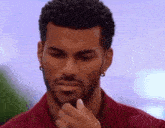 a man with a beard and earrings is holding his hand to his face .