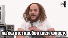 a man with long hair and a beard is sitting in front of a microwave and a television .