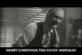 a man in a suit and tie is saying merry christmas you filthy animals !