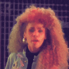 a woman with a very large afro is wearing a blue jacket