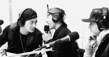 a group of young men wearing headphones are sitting in front of microphones .
