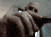 a bald man with a beard is holding a gun