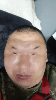 a man in a camo shirt looks at the camera with a serious look on his face
