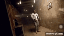 a man in a denim jacket is standing in a dark hallway with a picture on the wall