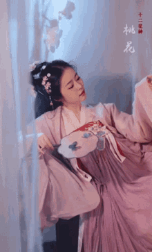 a woman in a purple dress is holding a fan with chinese writing on the bottom