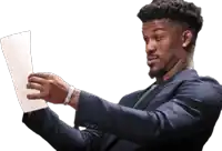 a man in a suit is holding a piece of paper in his hand