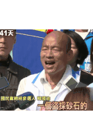 a bald man speaking into a microphone with chinese writing on the bottom right