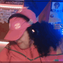a woman wearing a pink hat hugs another woman in front of a sign that says halloween