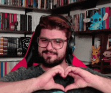 a man with glasses and headphones is making a heart shape with his hands