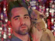 a man with a beard is holding a small brown dog in his arms .