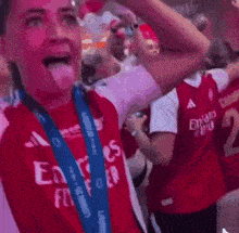 a woman wearing a red emirates fly emirates shirt holds a trophy in her hand .
