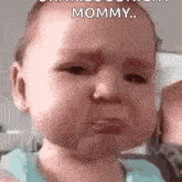 a baby is crying and looking at the camera while being held by a woman .